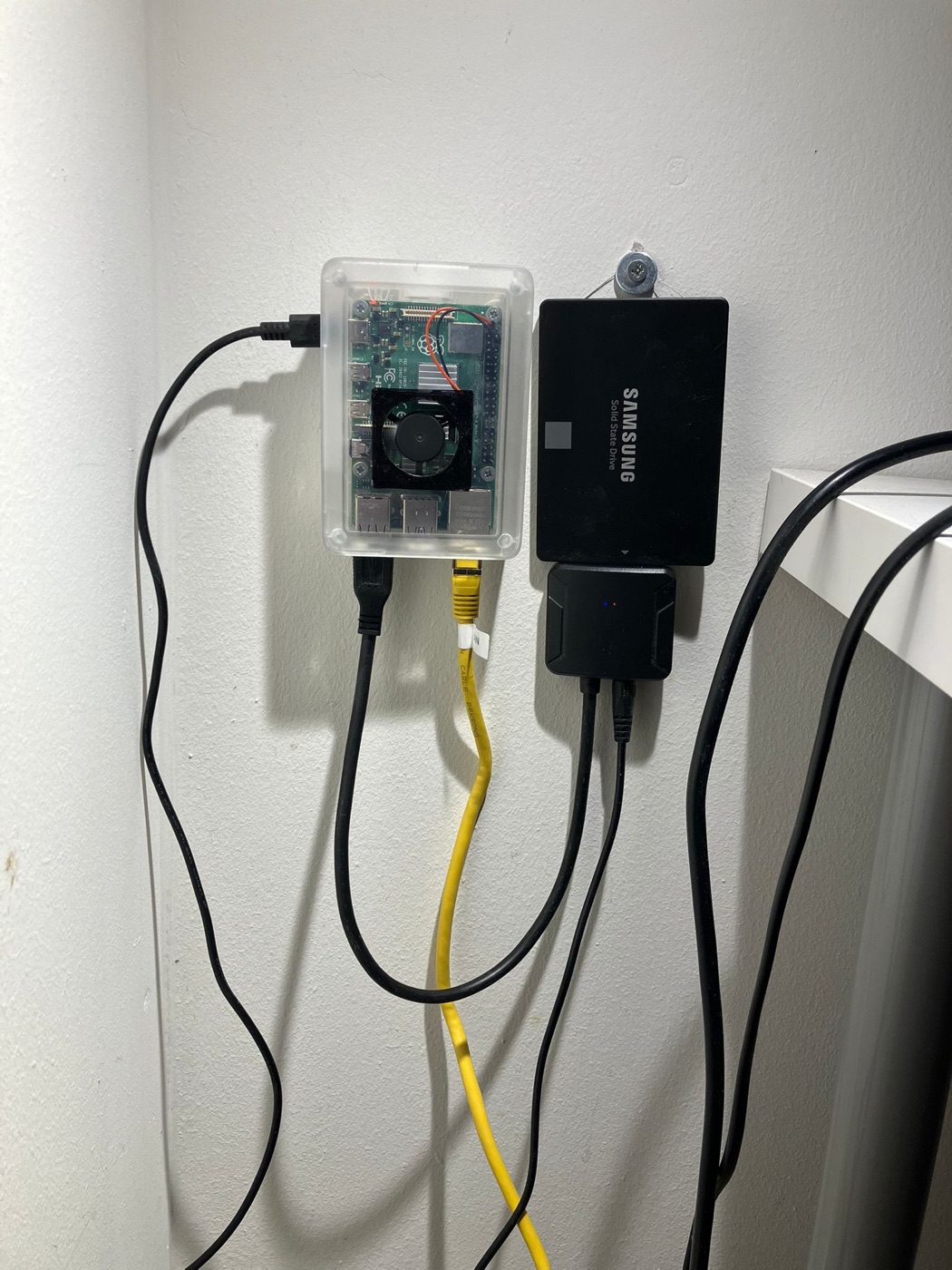 The Raspberry Pi mounted on the wall next to its SSD