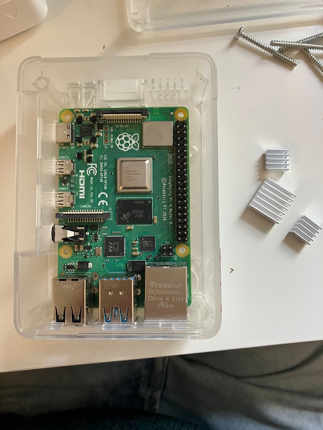 A Raspberry Pi 4 in its case, next to heatsinks and screws